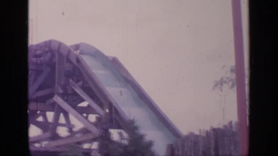 Faded 8mm frame from 1964 Flushing Meadows showing the upper section of a roller coaster structure before riders enter view.