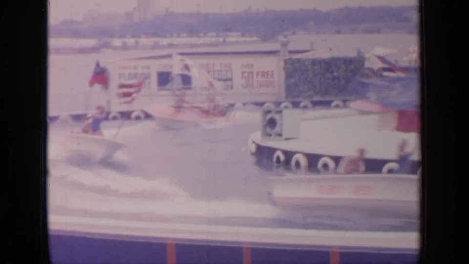 A 1964 New York World's Fair boat-race moment, with girls in low white boats and fair exhibit graphics behind the course.