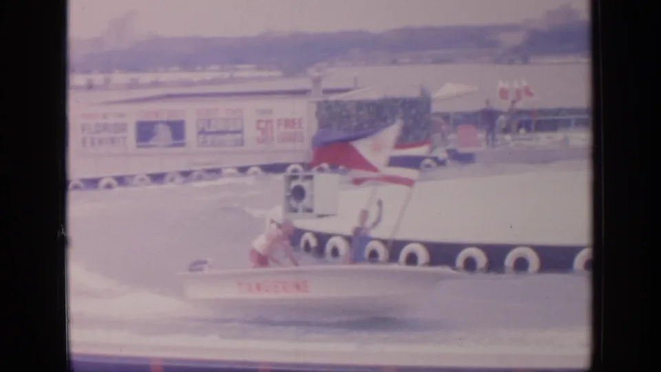 At Flushing Meadows in 1964, a speedboat marked Tangerine speeds past a platform and Florida Exhibit sign on a fairground water course.