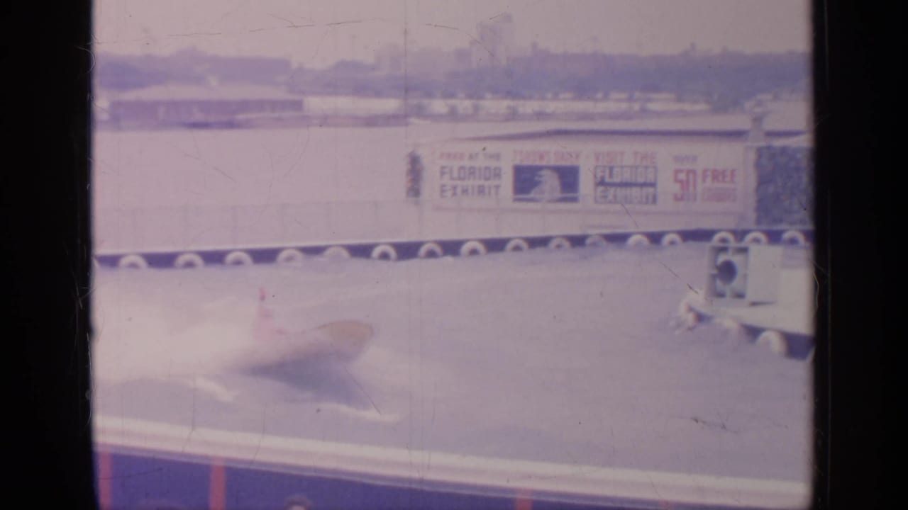 A blurred speedboat moves across the water course in front of the Florida Exhibit sign.