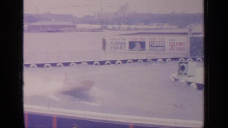 A fast-moving speedboat crosses the 1964 Flushing Meadows water course, blurred by motion with Florida Exhibit signage behind it.