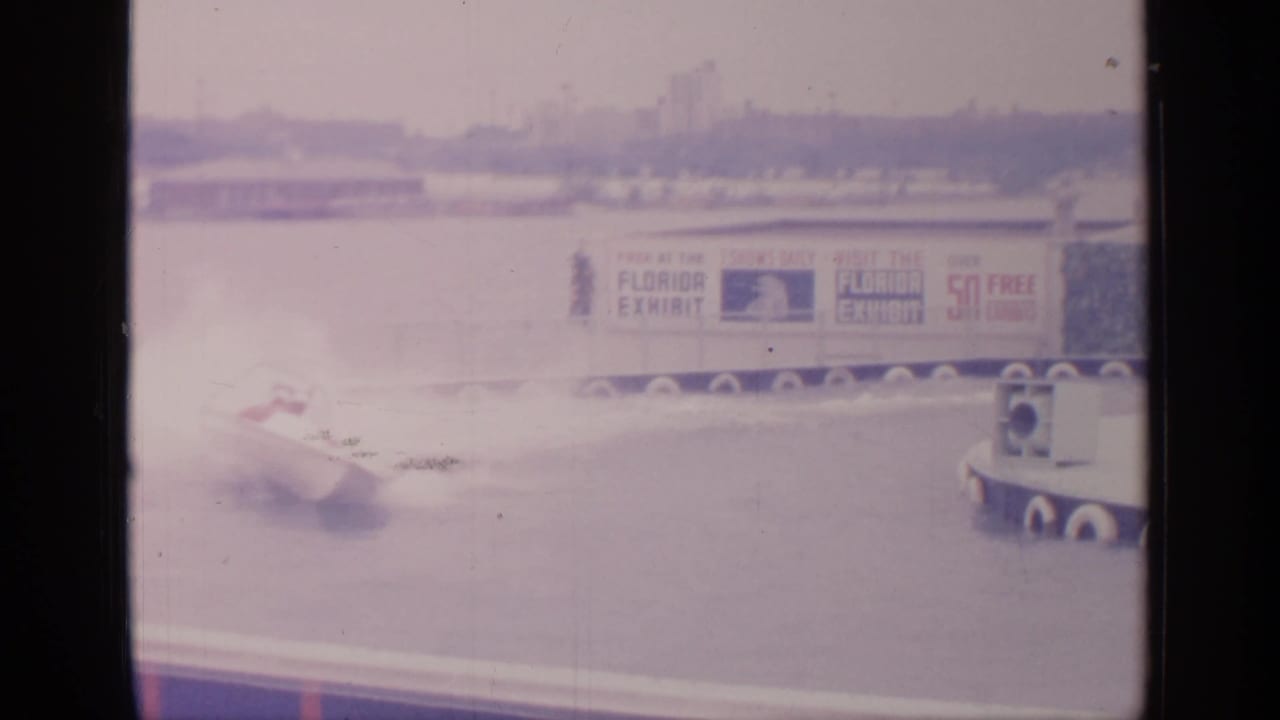 White speedboat near a Florida Exhibit banner on a fairground water track.