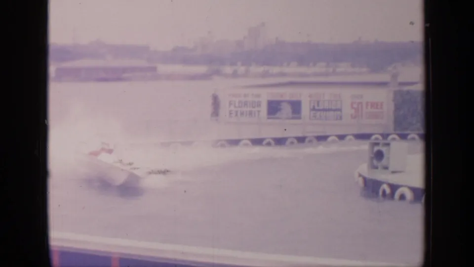At the 1964 Flushing Meadows World's Fair, a white speedboat passes near Florida Exhibit signage on a waterfront track.