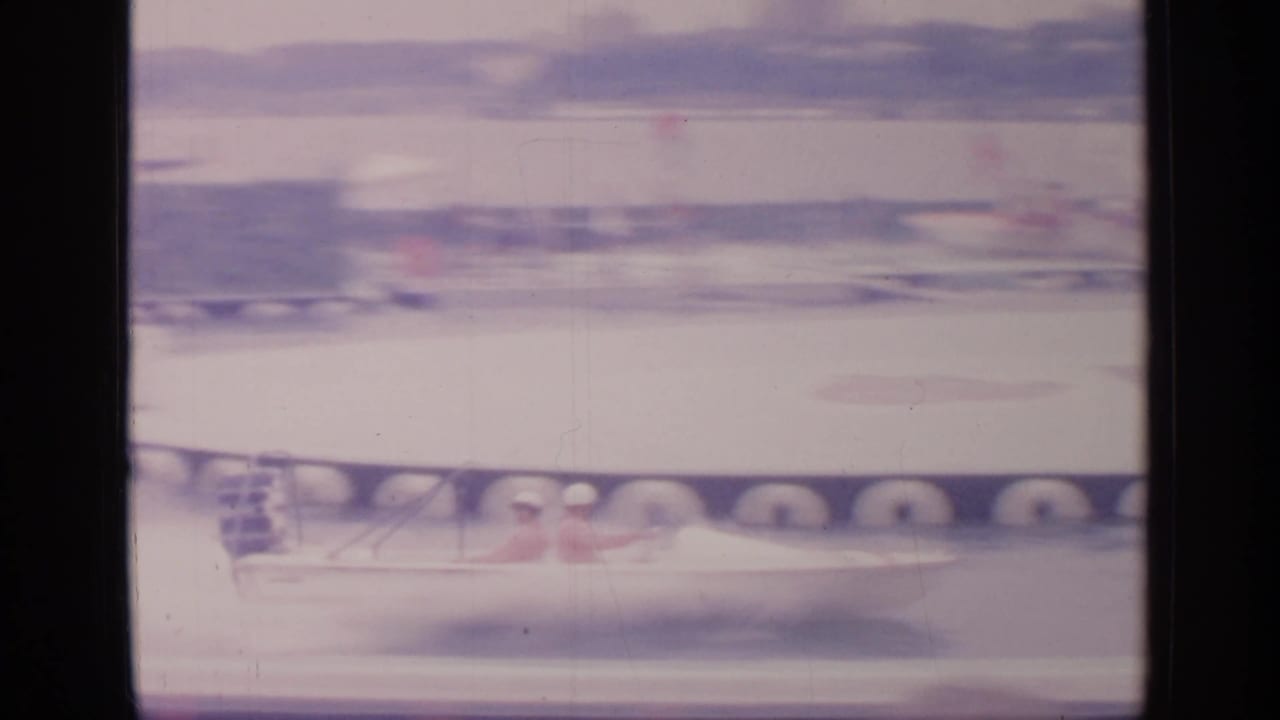 Blurred motorboat speeding past dock tires on a water track.