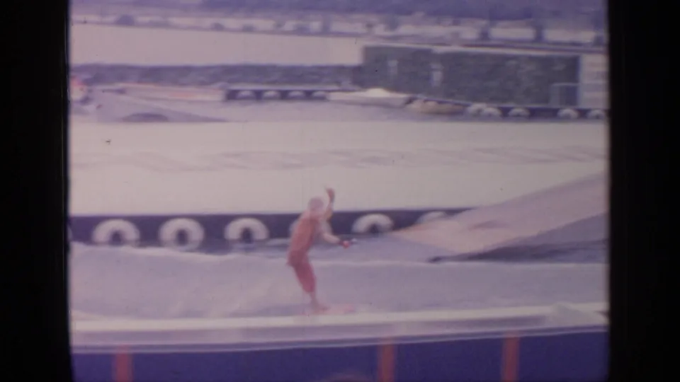 The skier continues along the Florida Exhibit pool near a sloped ramp, with fair structures and 8mm frame borders visible.