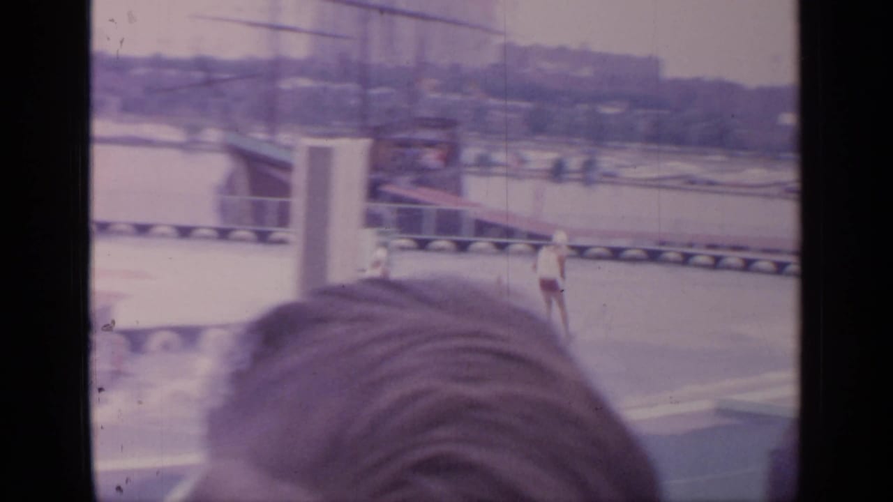 Water skier on a circular pool with spectators' heads in the foreground.