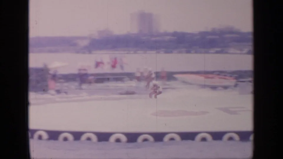 Home-movie frame from Flushing Meadows showing skiers and a tow boat crossing a circular performance pool.