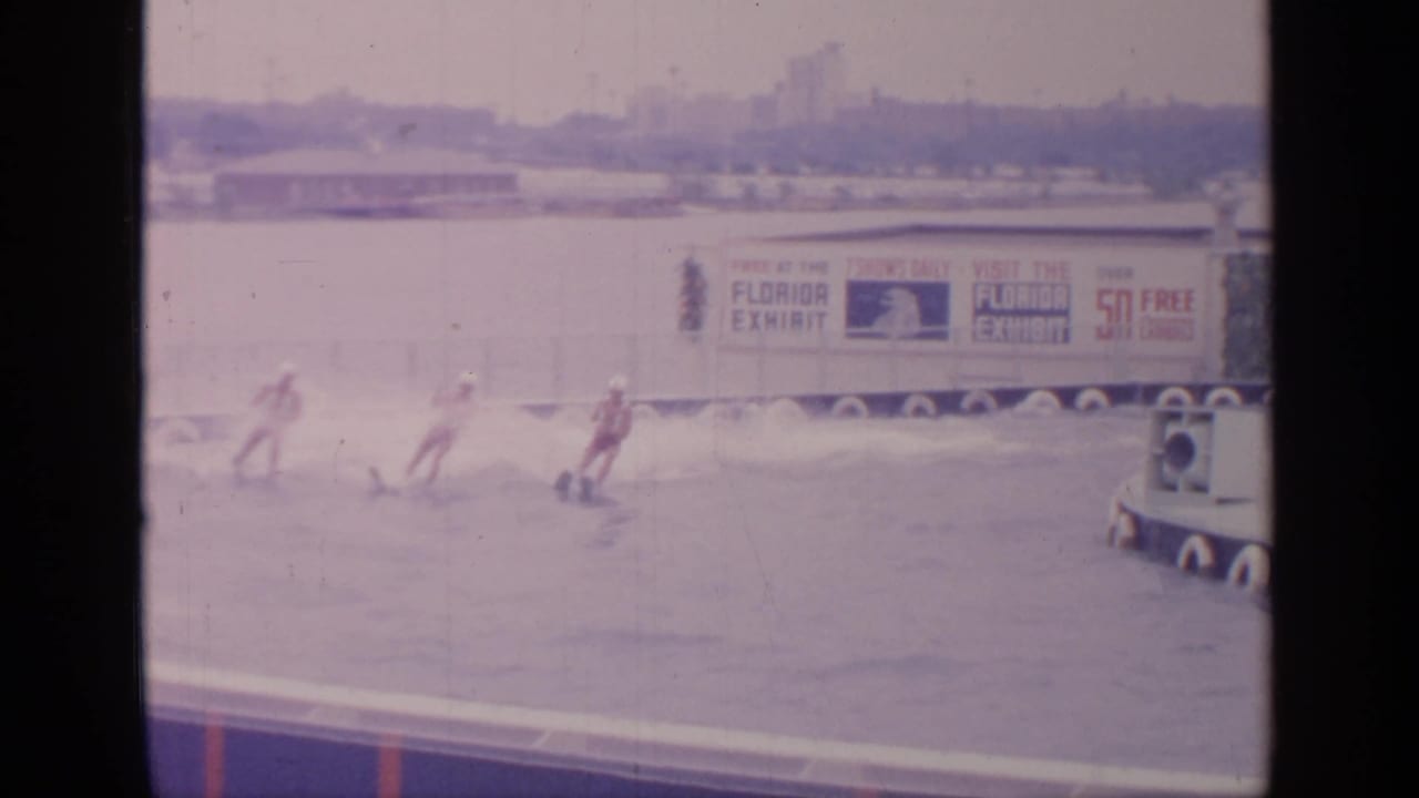 Water skiers pass near Florida Exhibit signage on a fairground lake.