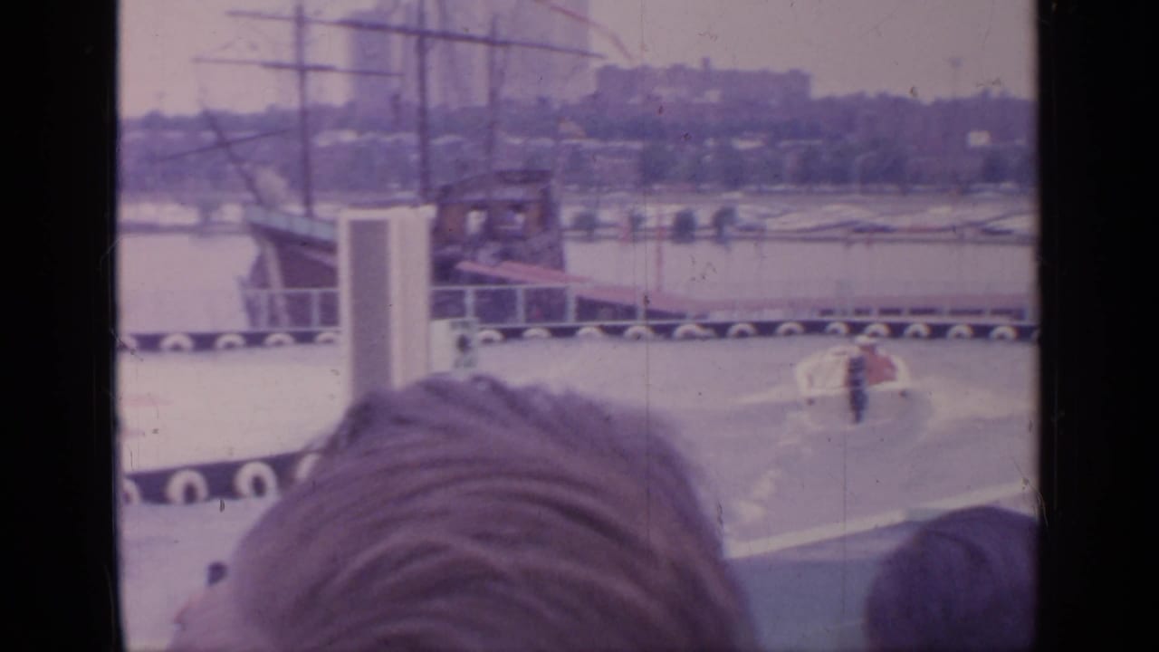 Spectators' heads frame a water performance area with a skier in the distance.