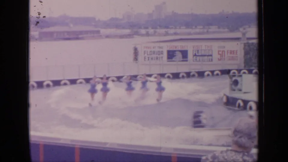 A line of female water skiers in matching blue outfits performs in front of Florida Exhibit signage at the 1964 Flushing Meadows fairgrounds.