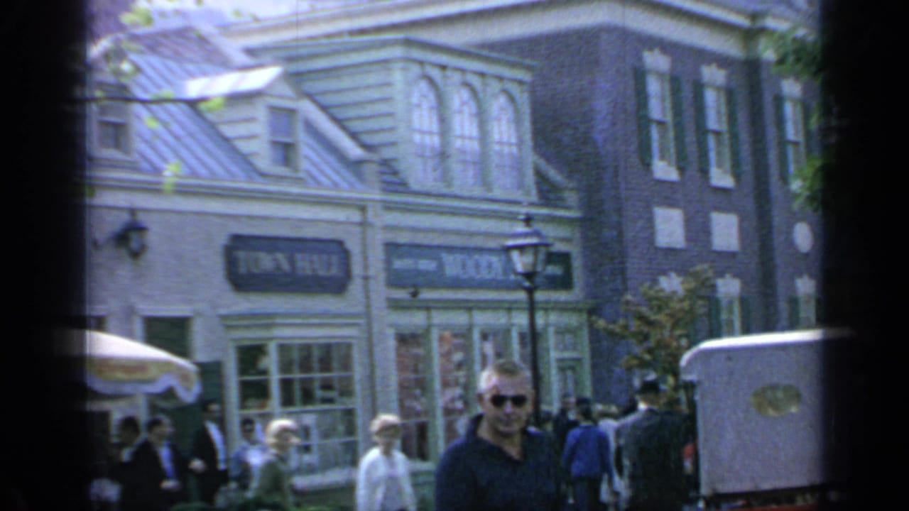 Visitors walk past fairground storefronts with Town Hall and Woody's signs visible.