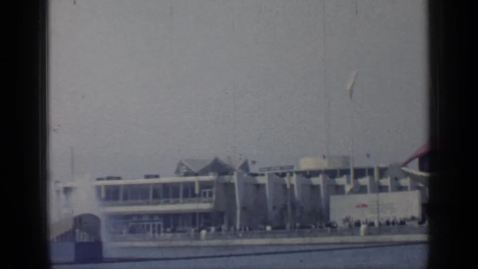 The pan reaches modern waterfront buildings with the red dome partly cropped at right, while small visitor groups remain visible near the promenade.
