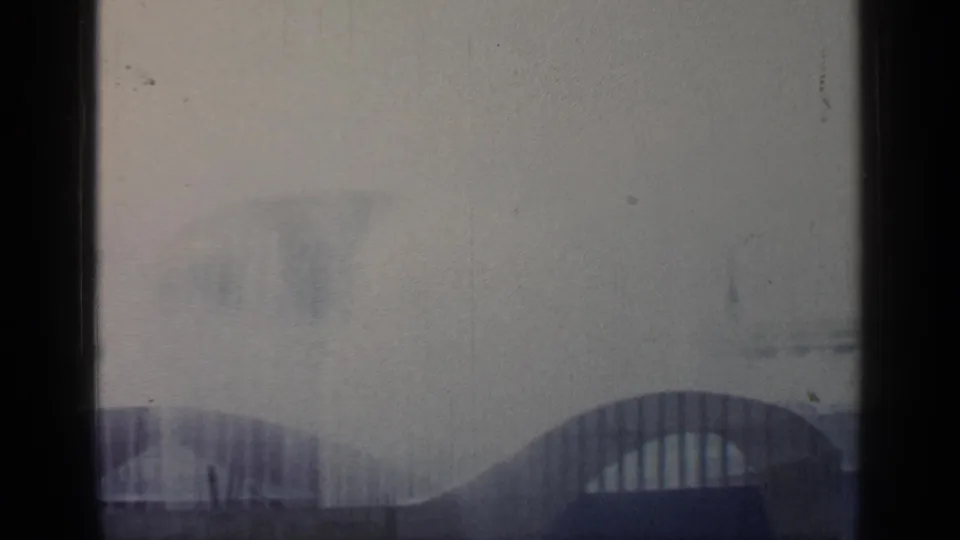 Soft 1964 Flushing Meadows view with arched World's Fair structures partly obscured by haze and dark frame edges.