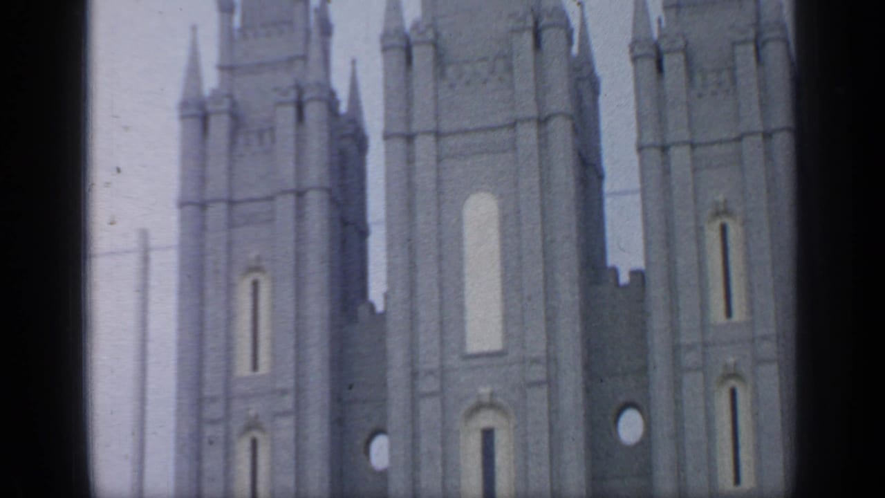 1964 Flushing Meadows home-movie frame showing pale spired towers with vertical panels and narrow openings.