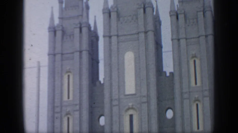 1964 Flushing Meadows home-movie frame showing pale spired towers with vertical panels and narrow openings.
