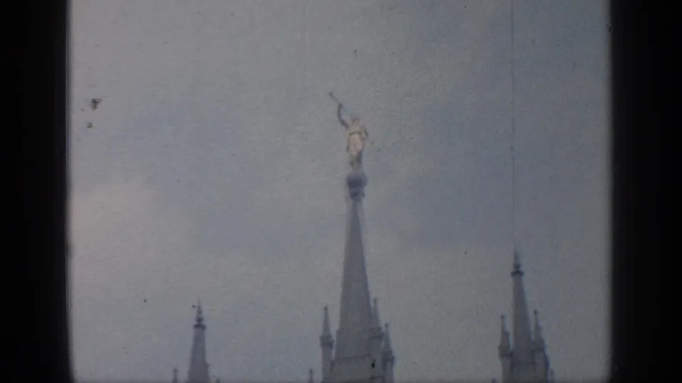 1964 Flushing Meadows frame showing a statue-topped column or spire rising above lower architectural towers.
