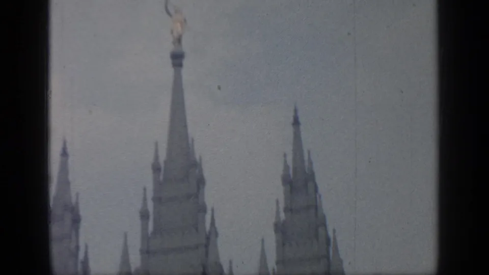 1964 Flushing Meadows footage showing pale pointed architectural towers against an overcast sky with 8mm film borders.