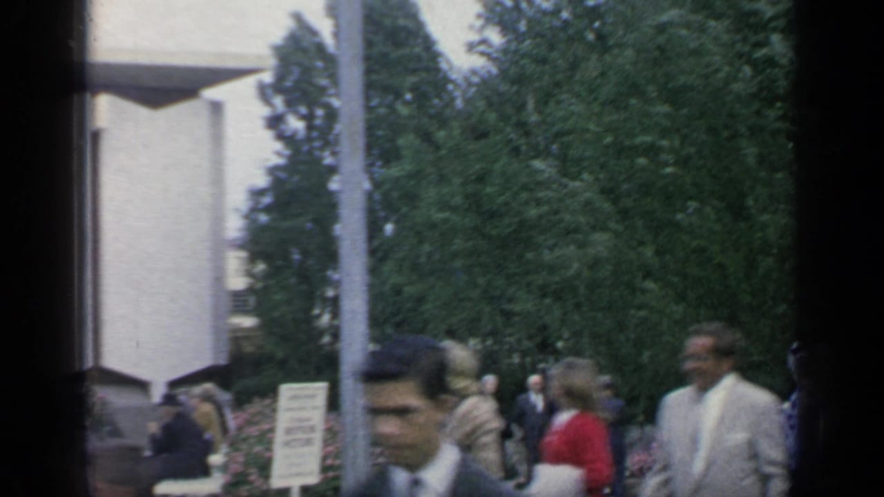 Fair visitors walking past trees and pavilion structures.