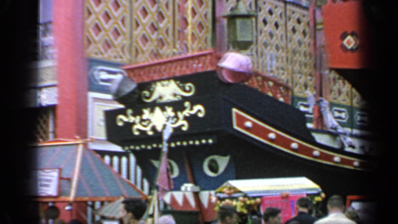 Crowds pass an ornate Chinese-themed pavilion with red columns and dark decorative signage.