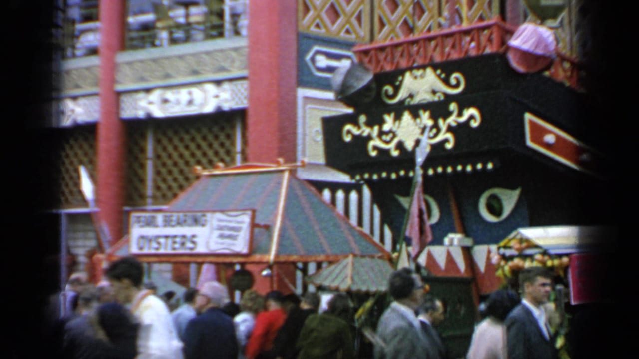 Fairgoers stand near a pavilion entrance and a sign advertising pearl-bearing oysters.