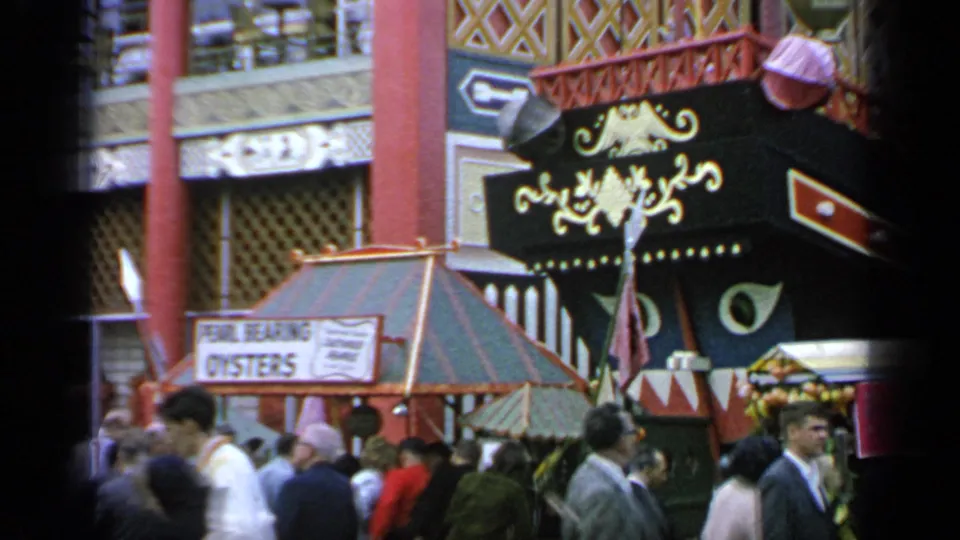 At the 1964 Flushing Meadows World's Fair, visitors pass a pavilion facade beside a visible pearl-bearing oysters sign.
