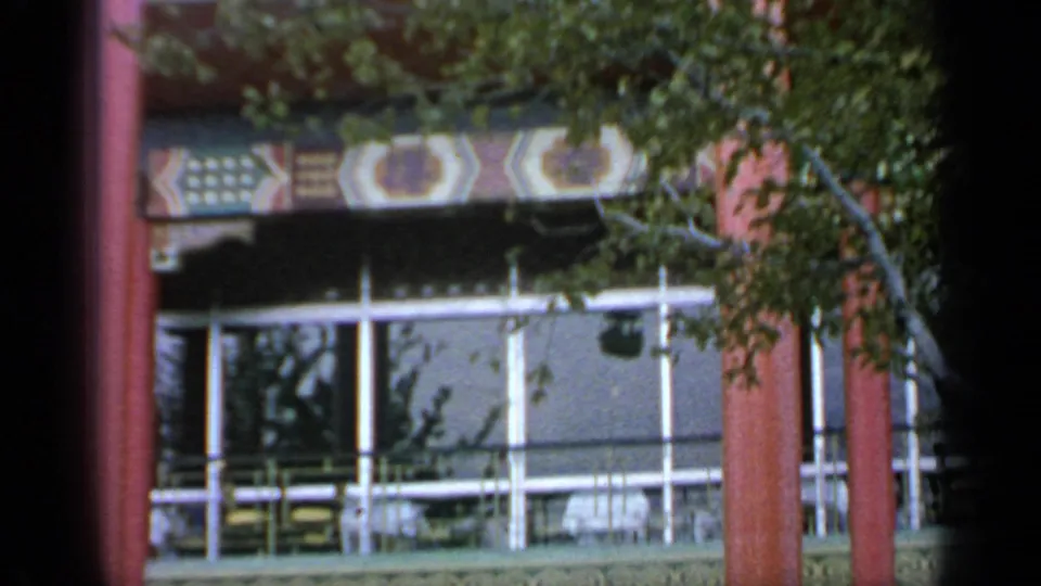 The final frame looks toward red pavilion columns, patterned trim, glass panels, and tree cover at the 1964 Flushing Meadows fairground.