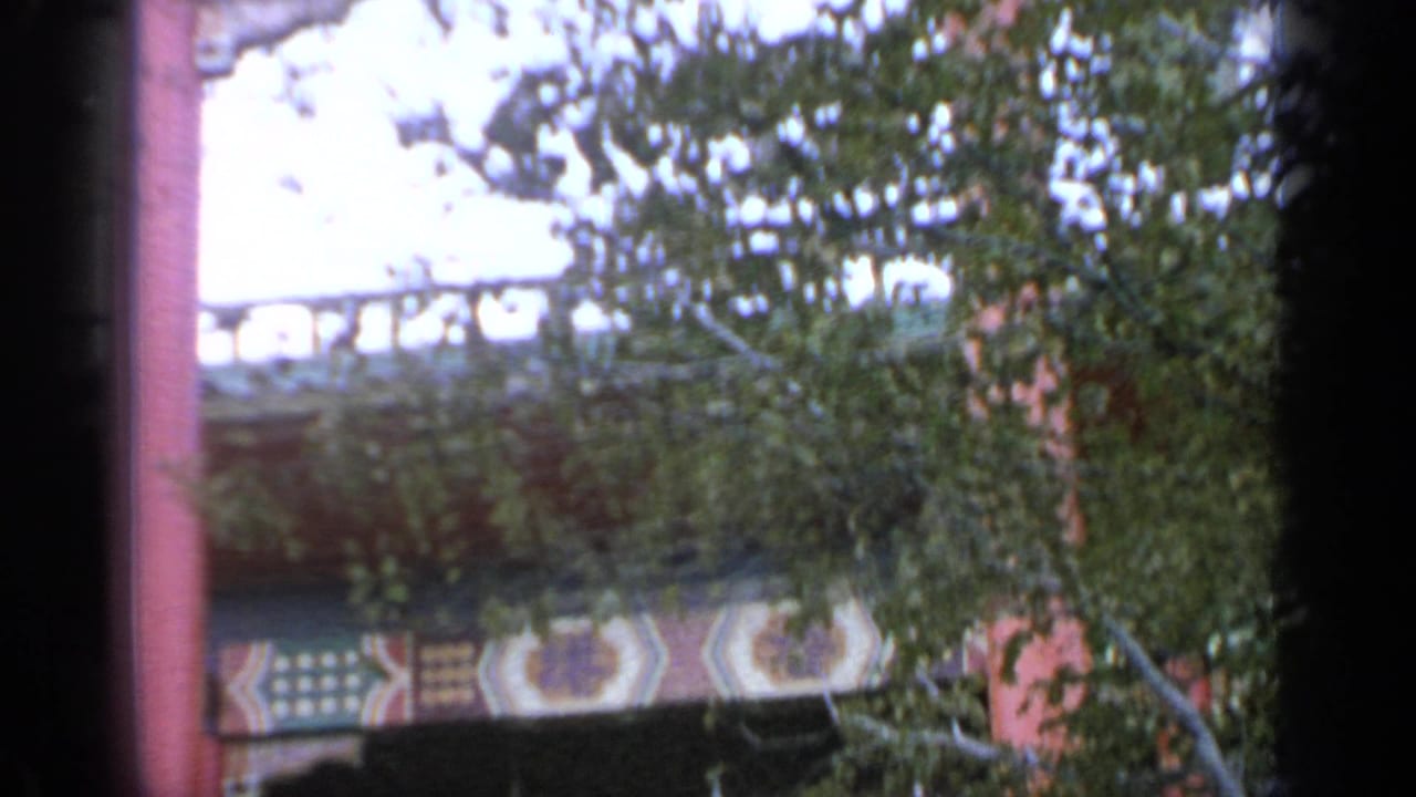Red columns and ornate fair structure partly obscured by leafy branches.