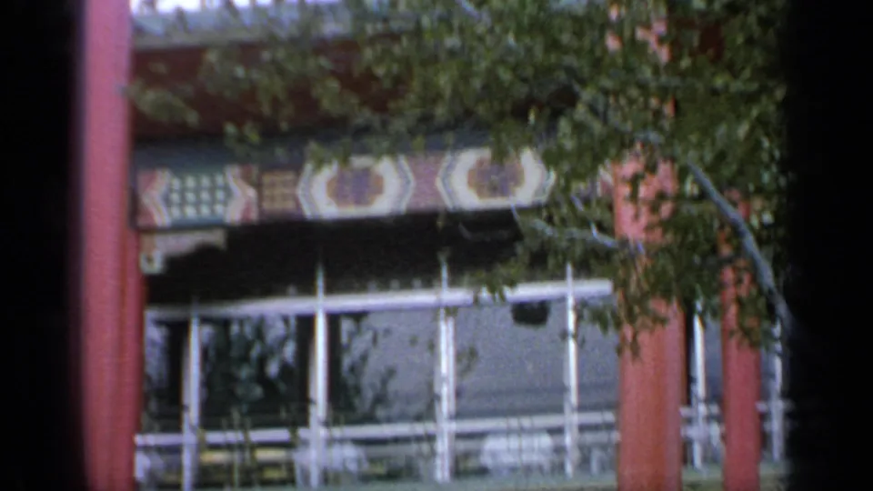 Red-columned fair building at Flushing Meadows in 1964, with branches crossing glass panels and decorative trim.