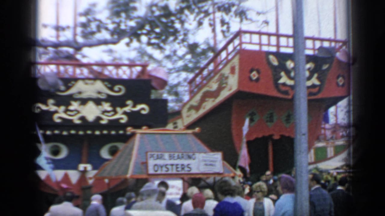 Ornate red and black fair structure with Pearl Bearing Oysters sign and visitors below.
