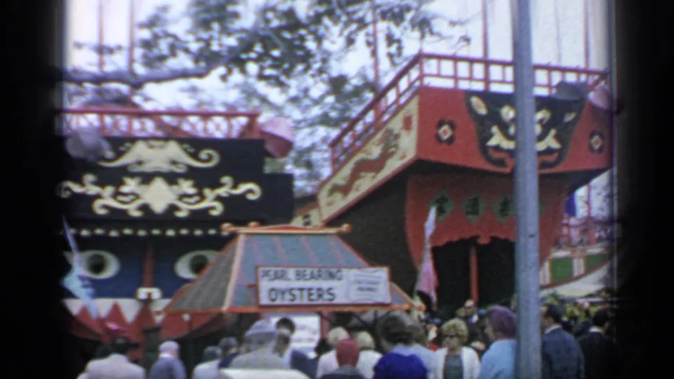 1964 New York World's Fair visitors stand below a Pearl Bearing Oysters sign and decorative boat-themed attraction facade.