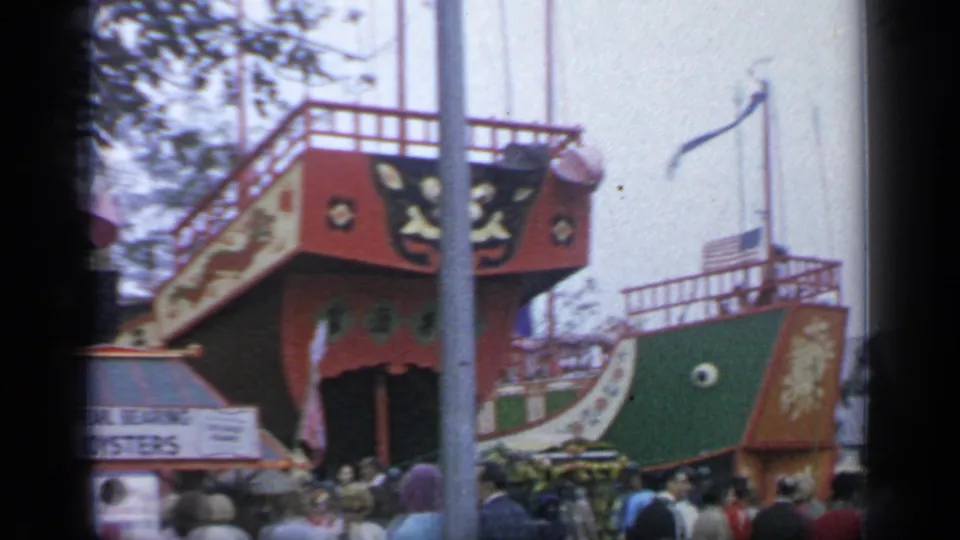 At Flushing Meadows in 1964, visitors move past colorful boat-themed fair architecture with the oyster sign partly in frame.