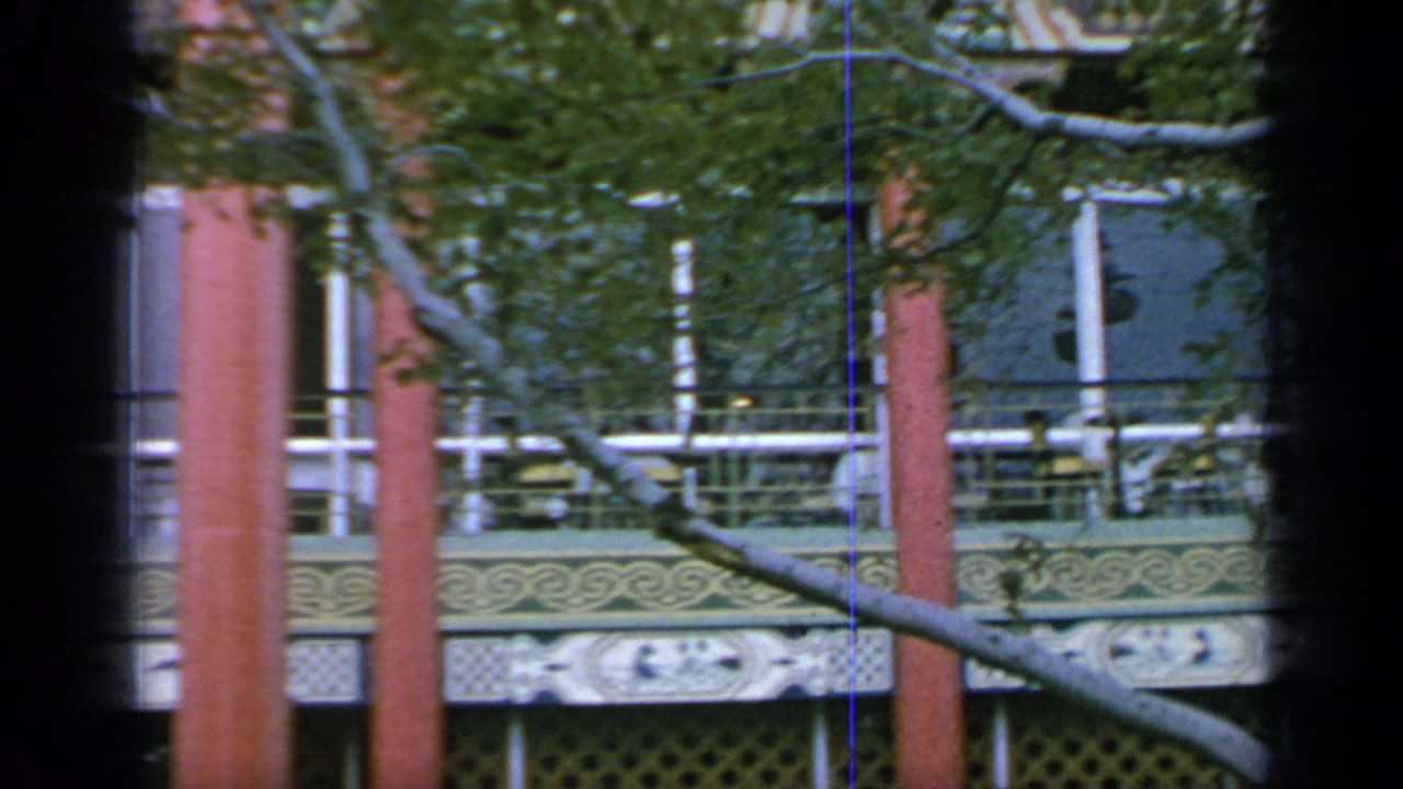 Red pillars, balcony railings, and branches across the pavilion exterior.