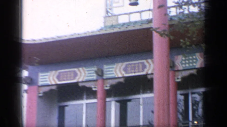 1964 home-movie view of red fairground columns, ornate eaves, and window bands at Flushing Meadows.