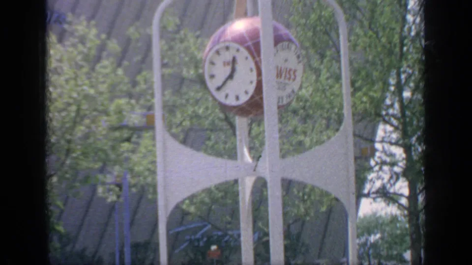 Closer 1964 Flushing Meadows view of the Wiss clock tower, with leafy trees and fair structures in the background.