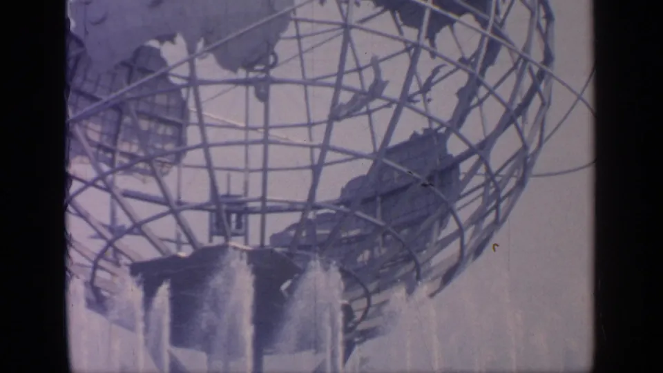 Faded 8mm frame of the Unisphere at Flushing Meadows, showing the globe structure above active fountain spray.
