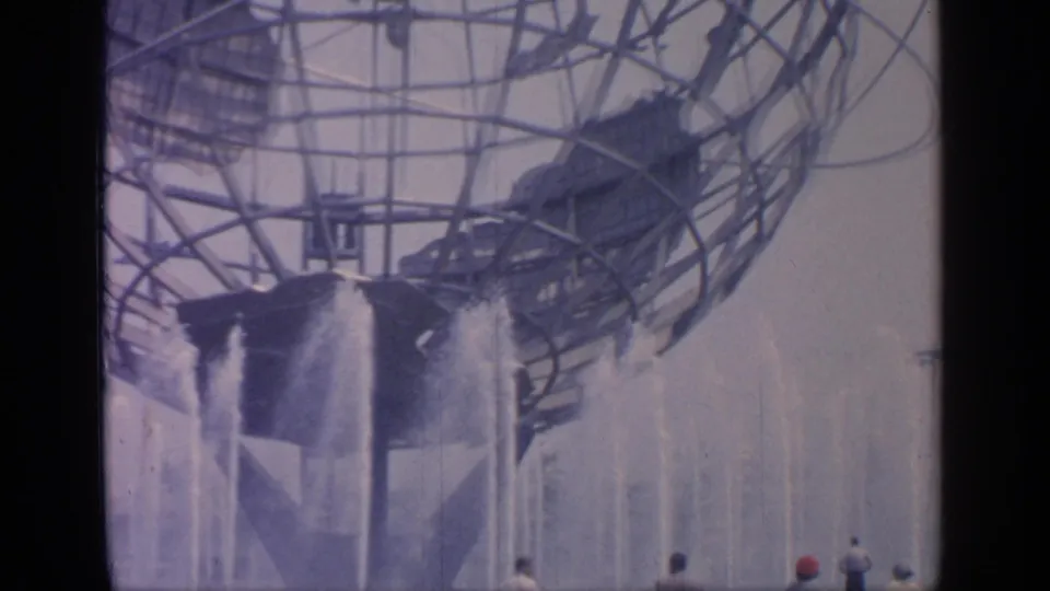 The Unisphere towers over fountains at the 1964 World's Fair, with small visitors visible near the lower right of the frame.