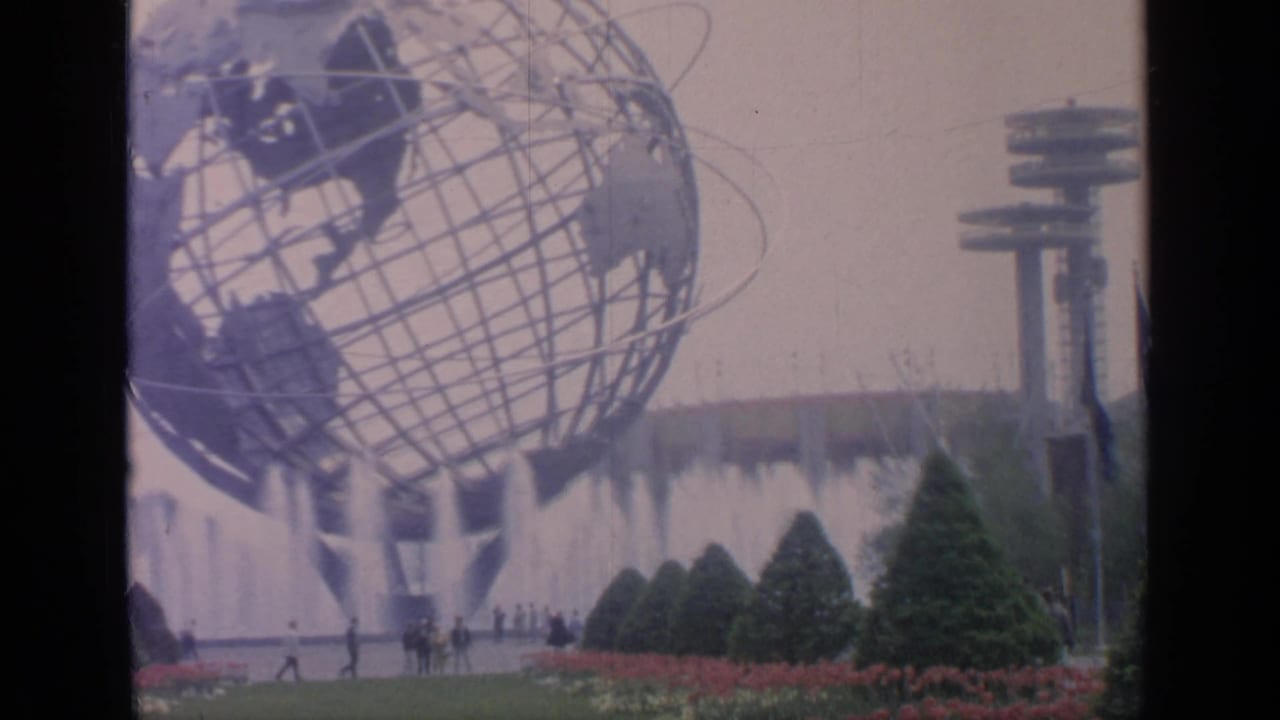1964 Flushing Meadows home-movie frame showing the Unisphere above fountains, gardens, and distant fair visitors.