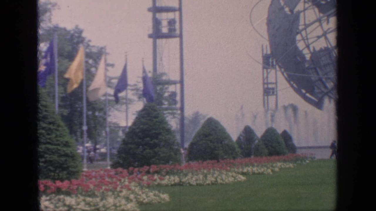 International flags, conical shrubs, flowerbeds, lawn, fountains, and part of the Unisphere.