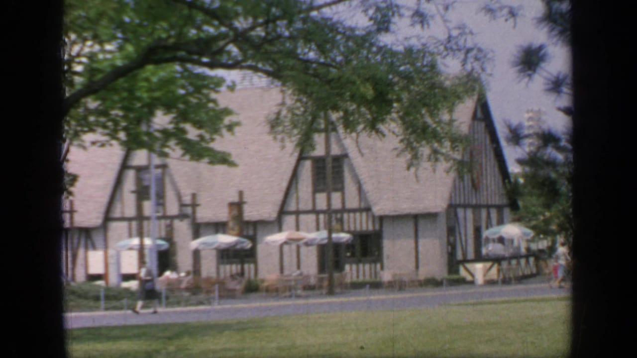 Tudor-style building with umbrellas and people along the walkway.