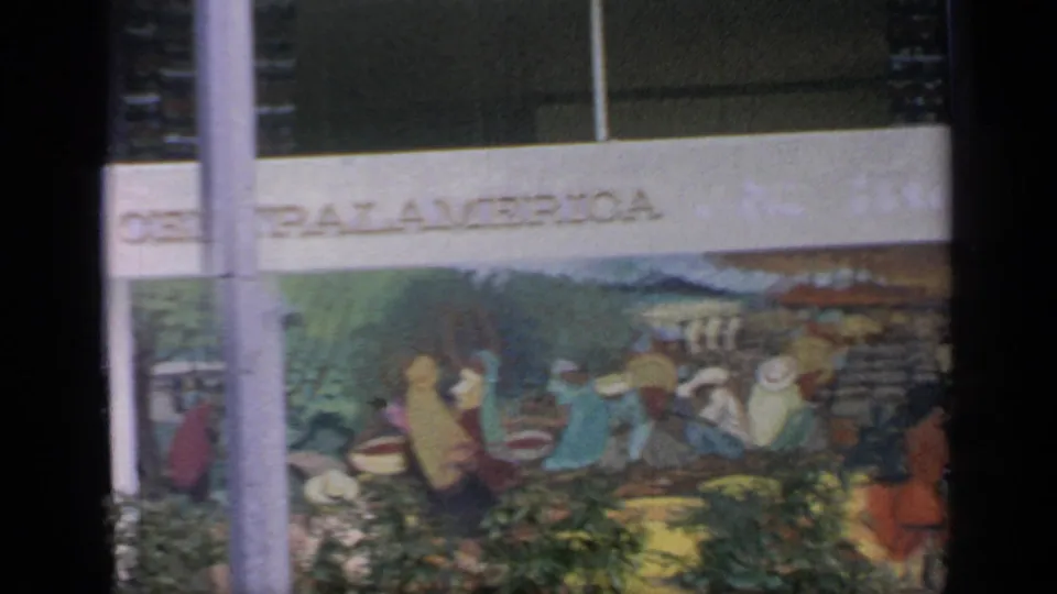 1964 Flushing Meadows fairground view of a Central America mural on a pavilion facade, partly obscured by posts and foliage.