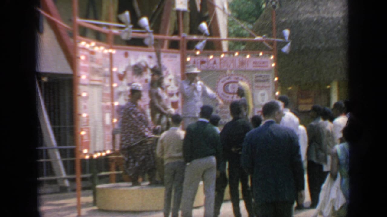 Crowd watches an illuminated pavilion display with costumed performers nearby.