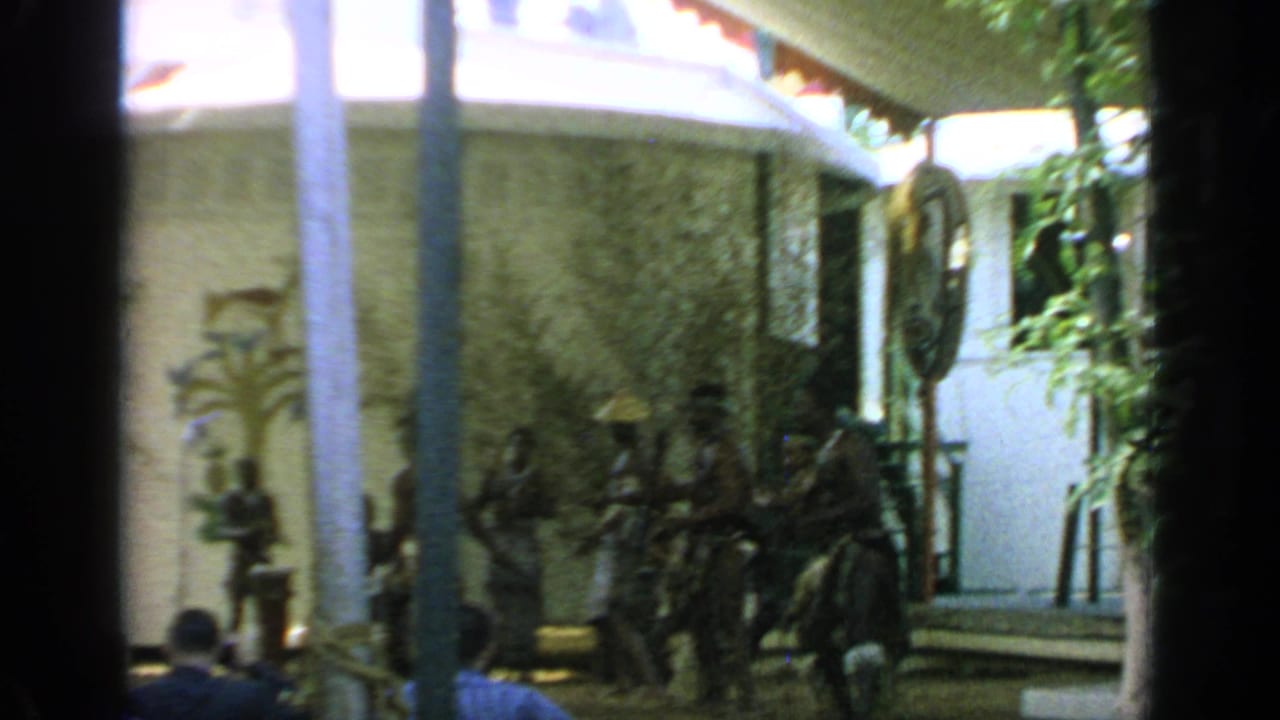 Group of performers in traditional attire moving near a decorated tented stage.