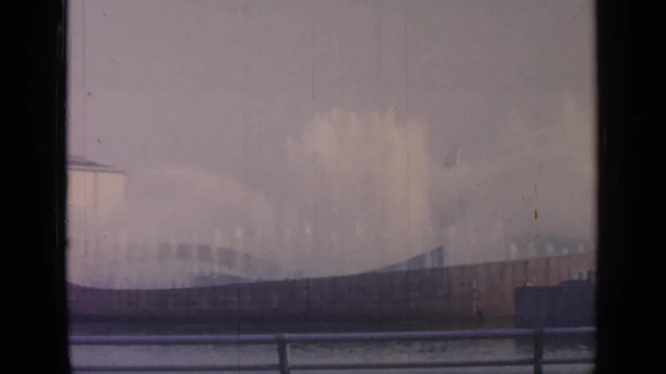 Misty fountain display at the 1964 Flushing Meadows World's Fair site, with curved basin edge and foreground railings visible.