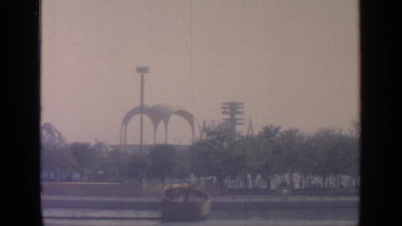 Distant pavilion arches seen beyond trees and a roadway.