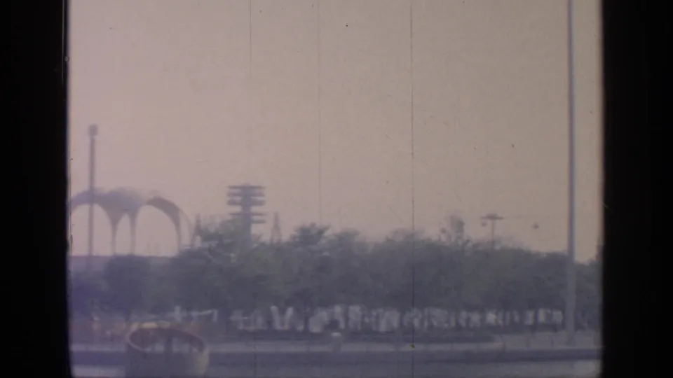 Distant New York State Pavilion arches and fairground plantings appear in a soft 8mm view of Flushing Meadows.