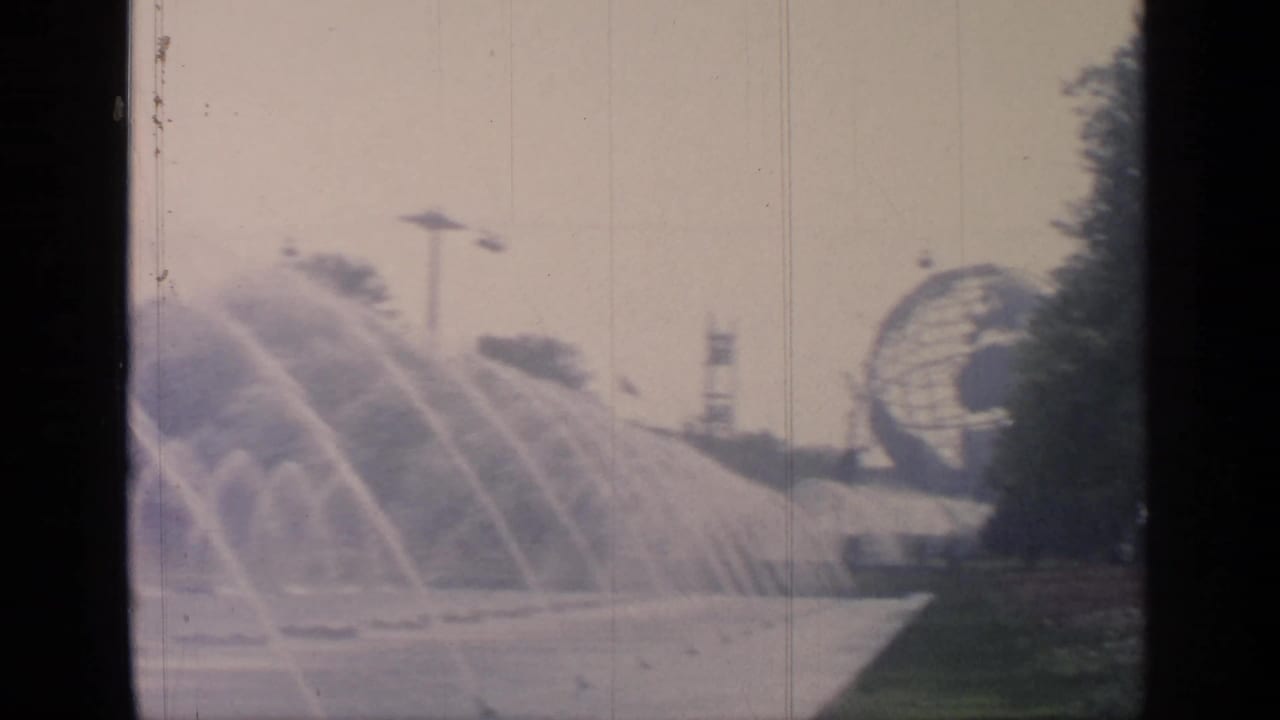1964 Flushing Meadows World's Fair view of the Unisphere behind broad fountain sprays and landscaped paths.
