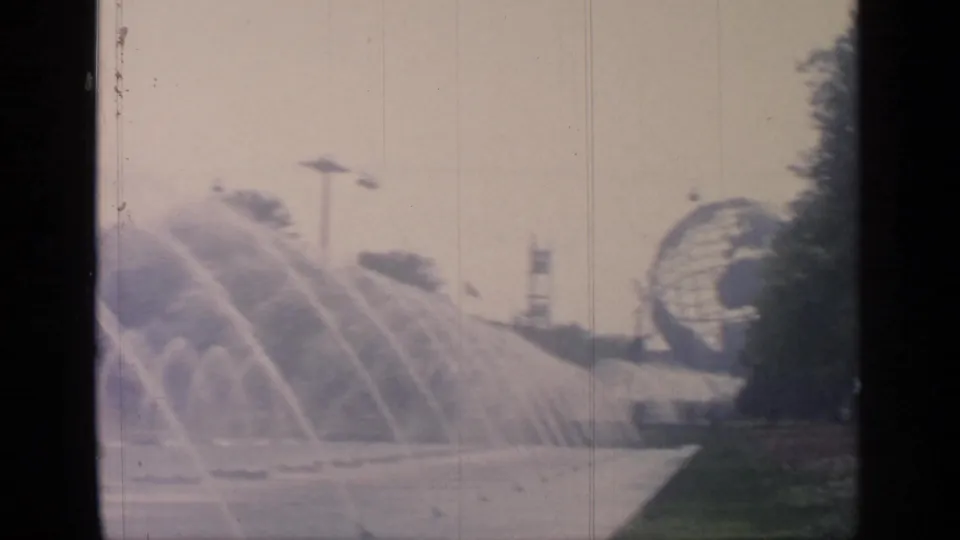 1964 Flushing Meadows World's Fair view of the Unisphere behind broad fountain sprays and landscaped paths.