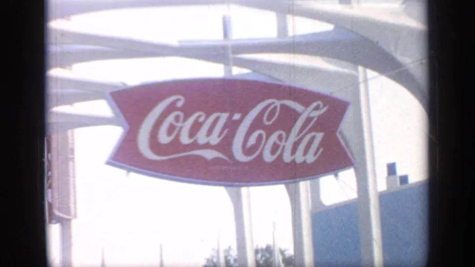 A Coca-Cola sign appears on a bright modern fairground structure in the 1964 World's Fair footage.