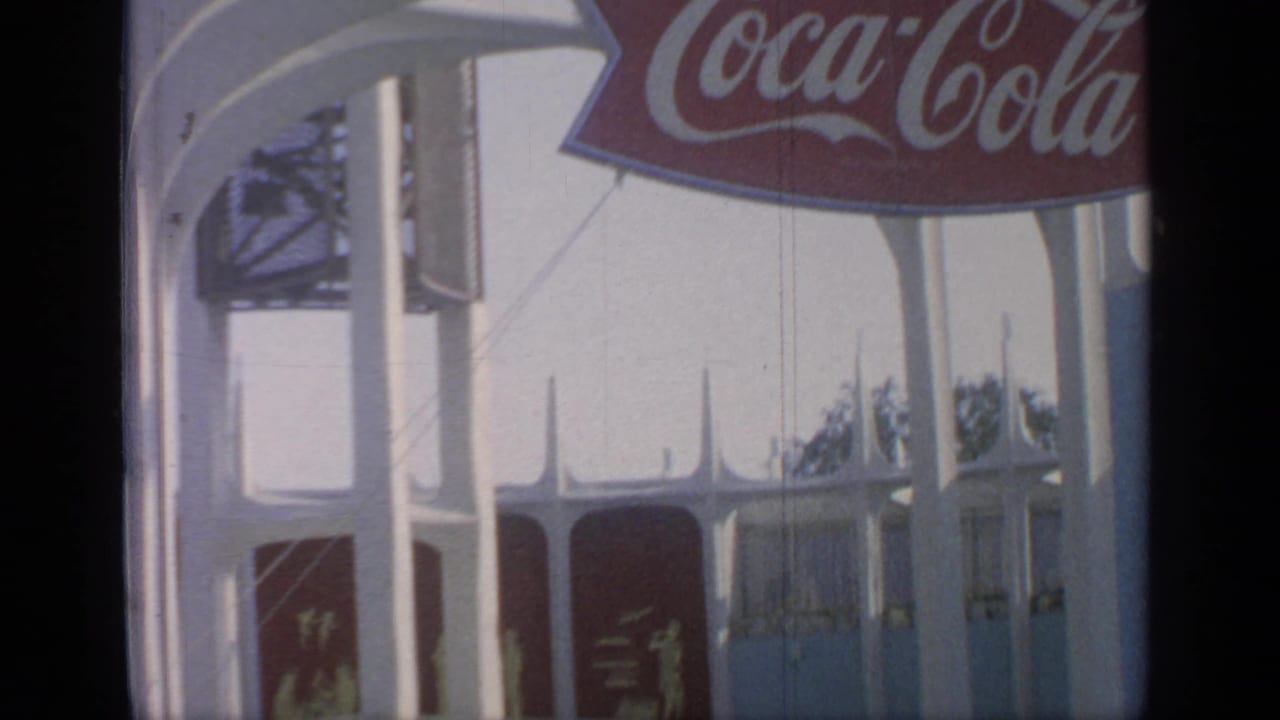 Coca-Cola sign above white fair pavilion columns with red panels below.
