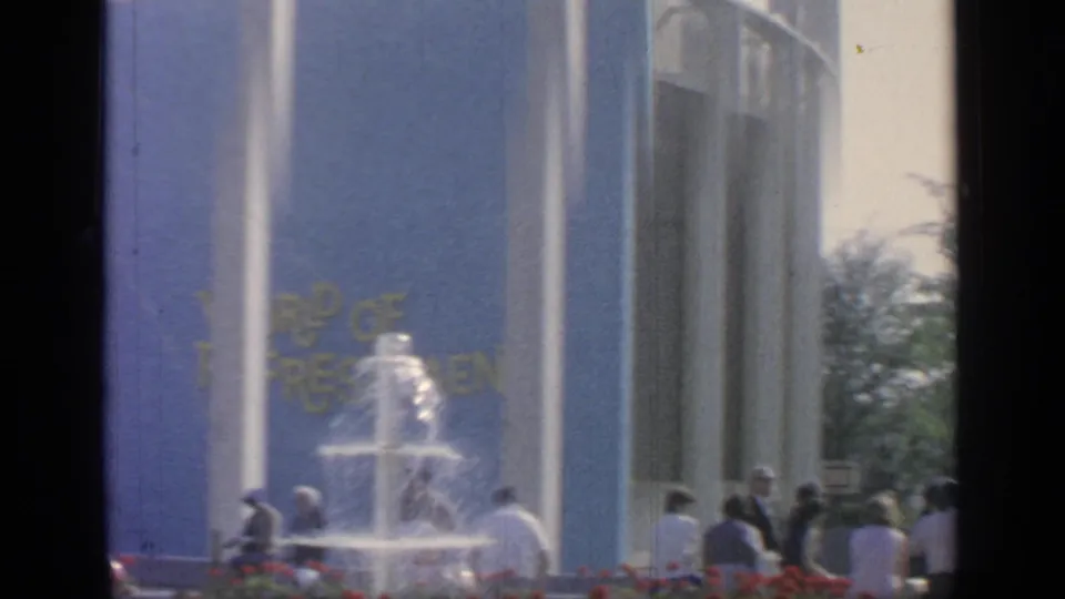 Visitors stand near a tiered fountain and blue pavilion wall at the 1964 Flushing Meadows fairgrounds.